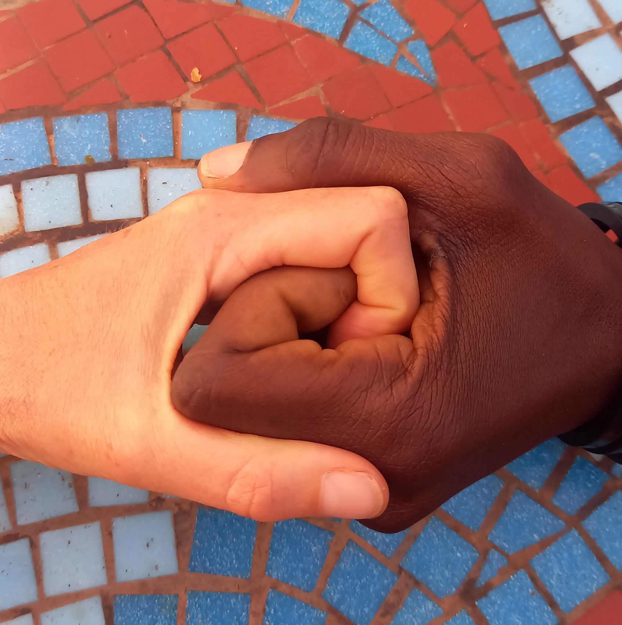 Deux mains qui se tiennent sur une mosaïque colorée